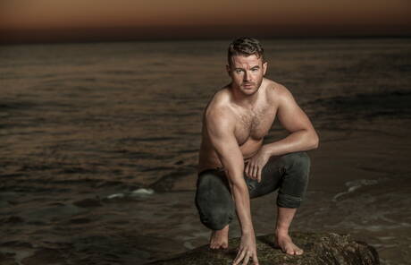 Amerikaanse otter Alexander Greene en Ierse harige beer Brendan Patrick poseren naakt op het strand