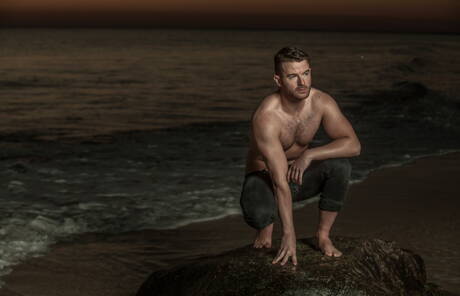 Amerikaanse otter Alexander Greene en Ierse harige beer Brendan Patrick poseren naakt op het strand