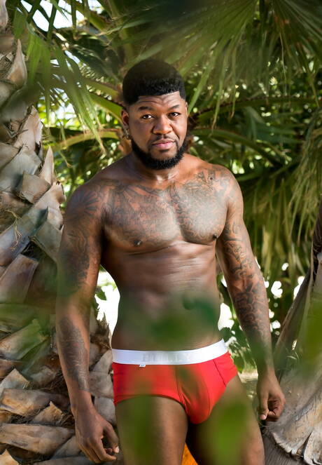 Black muscular Mr. Cali shows a husky body outdoor